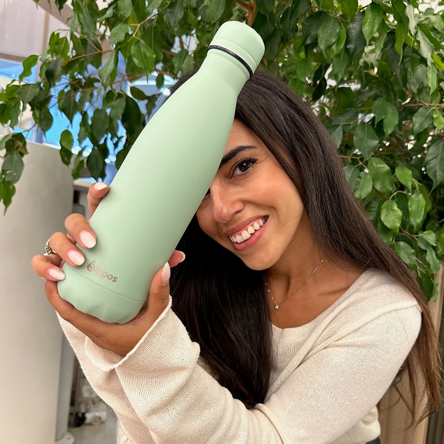 Усмихната жена, която показва термос бутилка All Green 